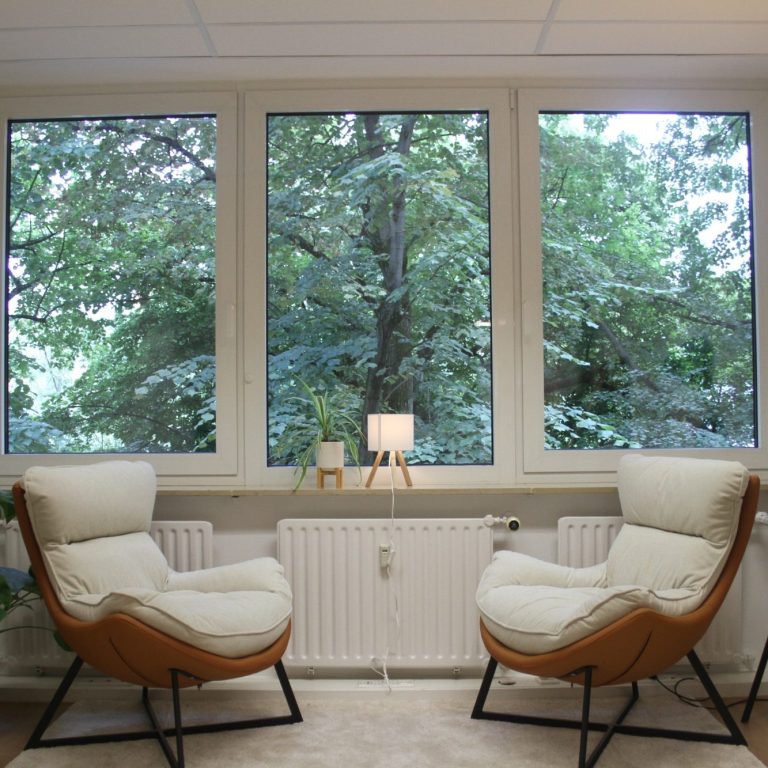 Zwei bequeme Sessel vor einem Fenster mit Blick auf Bäume und Natur.